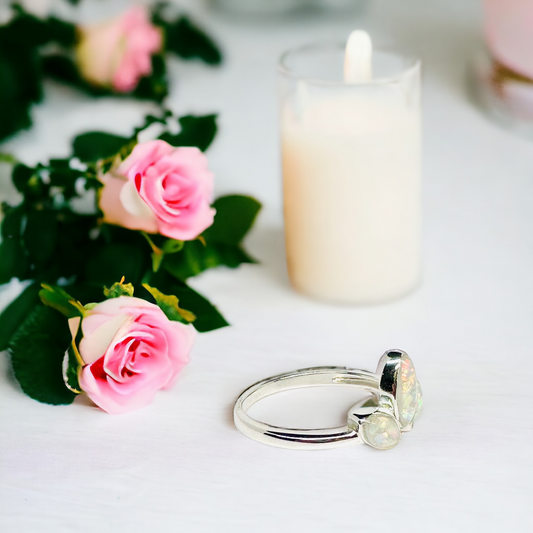 Side view of the Tiara 3 Stone Cremation Ring in Sterling Silver on a table, showcasing the elegant marquise-shaped pearl white crushed opal stones and the ring's intricate design, reflecting a timeless tribute.