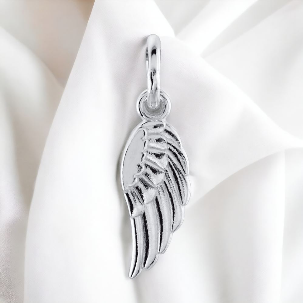 Sterling silver angel wing charm with a mirror-like finish, gracefully displayed on a smooth fabric, capturing the essence of a cherished memory.