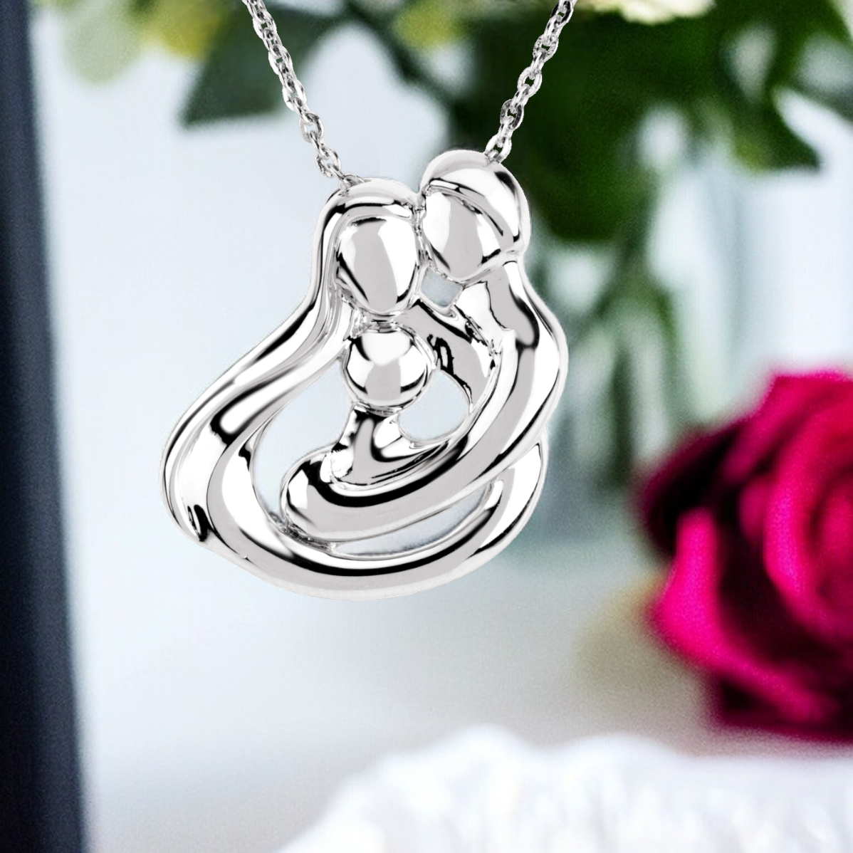 Sterling silver family embrace pendant on a soft background, depicting a fluid hug design with one child, from Deborah J. Birdoes' collection.