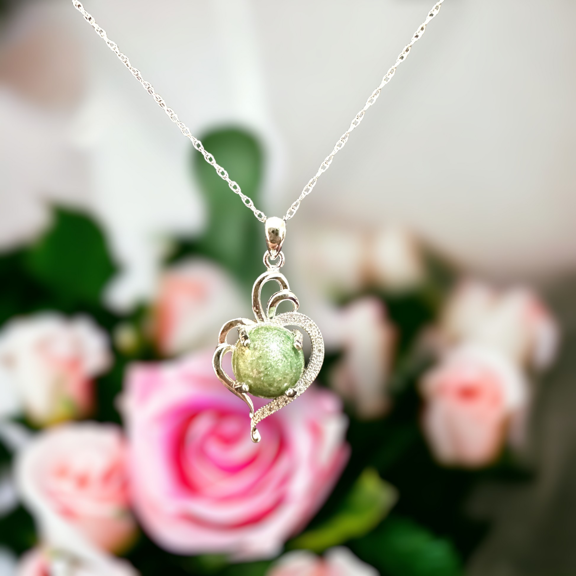 Closeup of Radiant Heart pendant hanging, adorned with a round moss green cremation stone in sterling silver, capturing the essence of everlasting bonds and nature's tranquility.