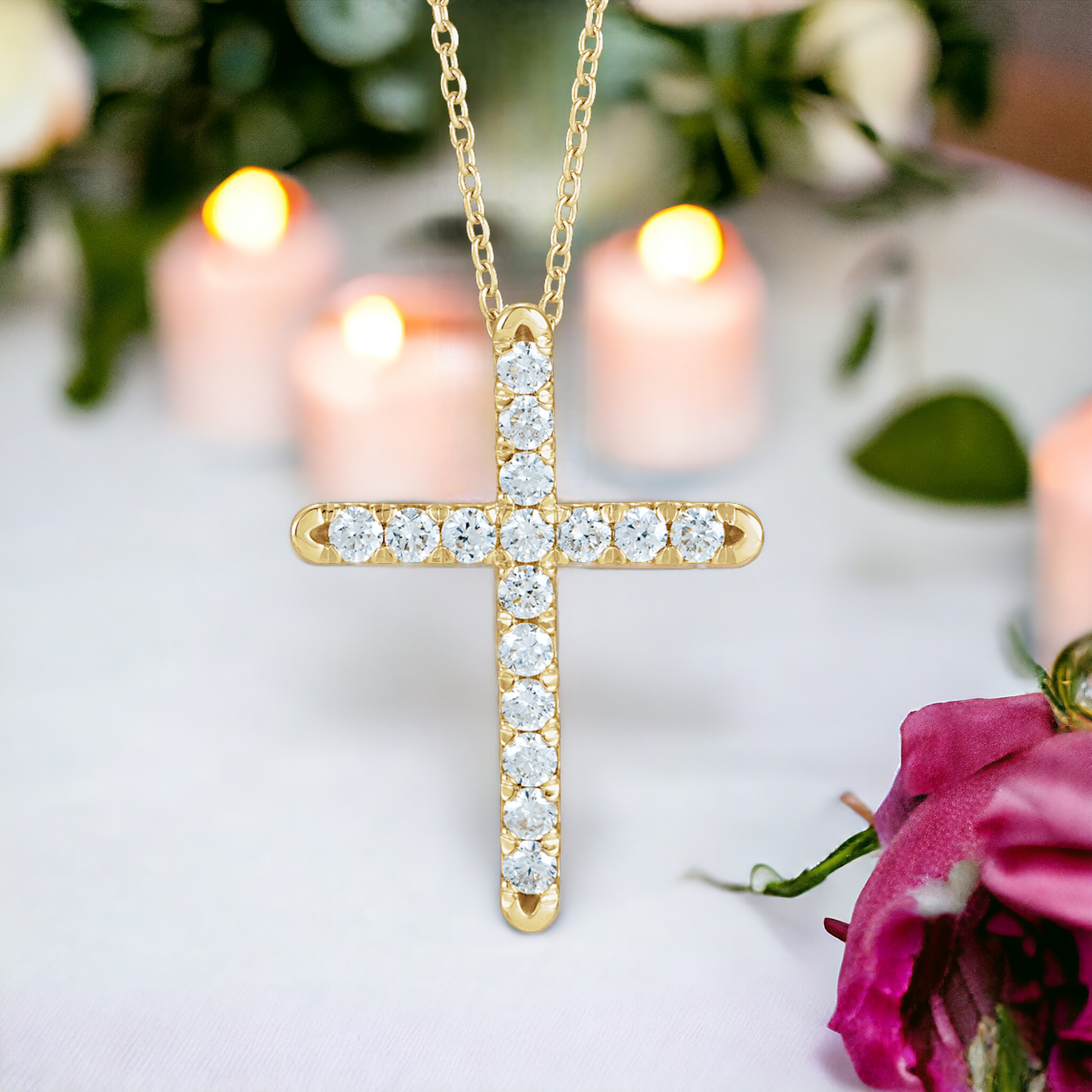 Gold diamond cross necklace with a soft-focus background featuring a candle and pink roses, symbolizing warmth and faith.