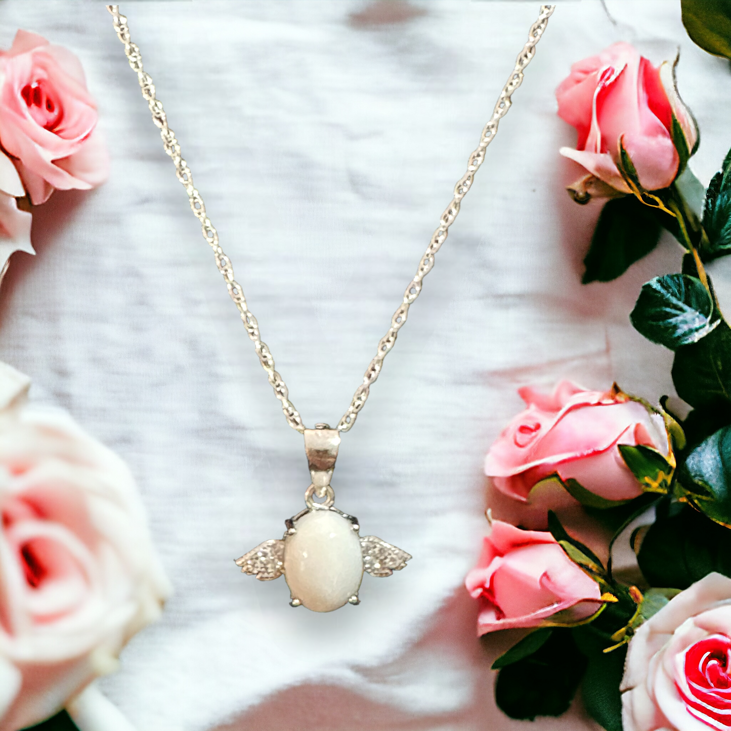 Closeup view of the Angel's Touch necklace in silver, displaying a pearlescent white breastmilk stone between delicate angel wings, representing the nurturing bond and love.