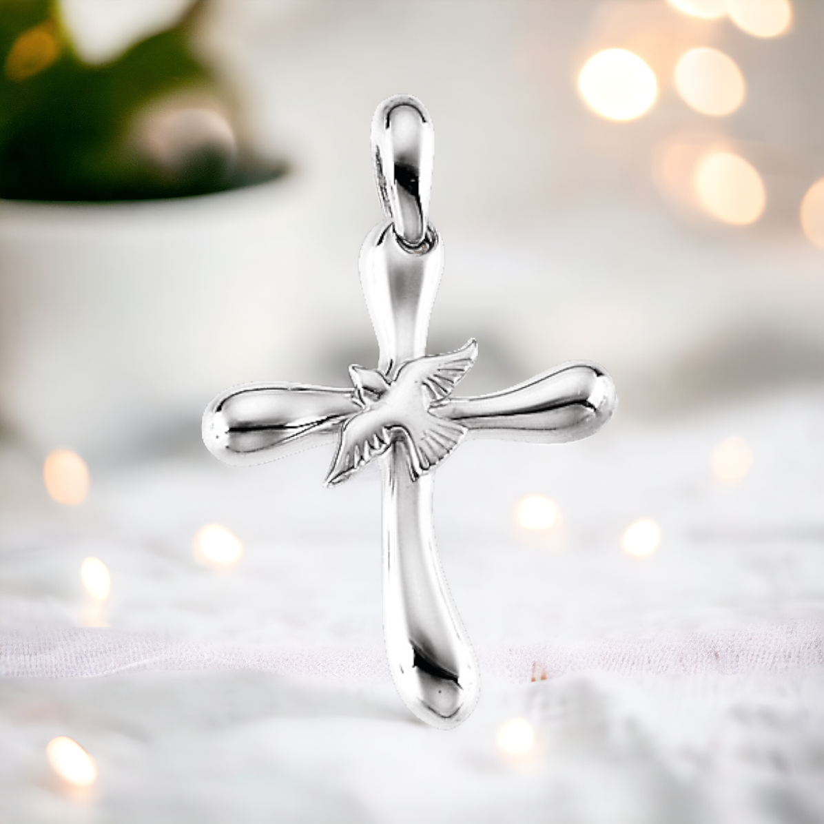 Reflective sterling silver cross pendant with a dove detail, representing tranquility and the divine.