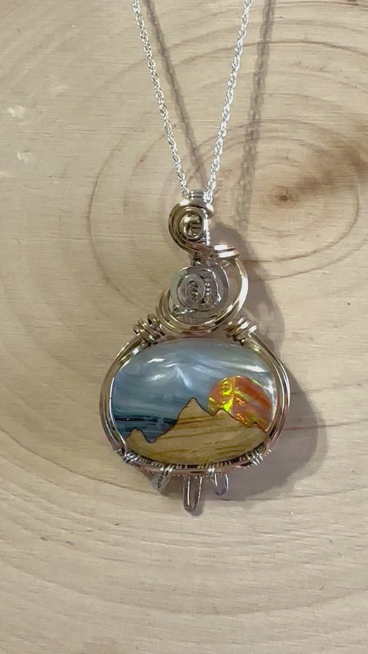 Rotating view of the Southwestern Mountain  pendant necklace on a wooden background, highlighting the multi-layer design and the vibrant colors of the aurora opal and mother of pearl.